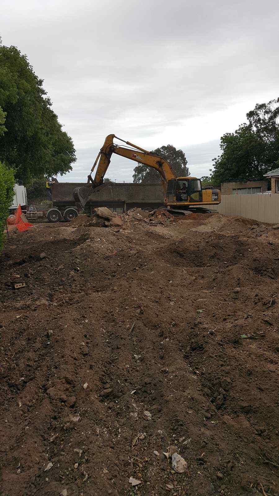 Excavator loading demolition debris on a residential site